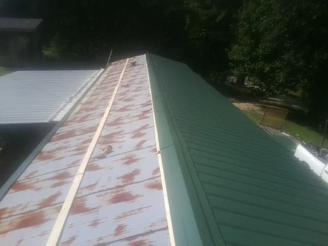 Old rusted panels beside newly installed green metal roofing — Wind Damage Roof Repair by Roofing Brothers in Summerhill
