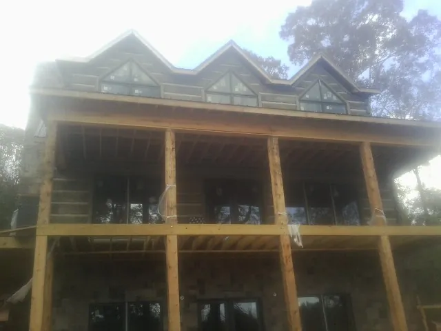 Dormers and porch framing on a large log home under construction — Roof Coating work by our crew in Summerhill