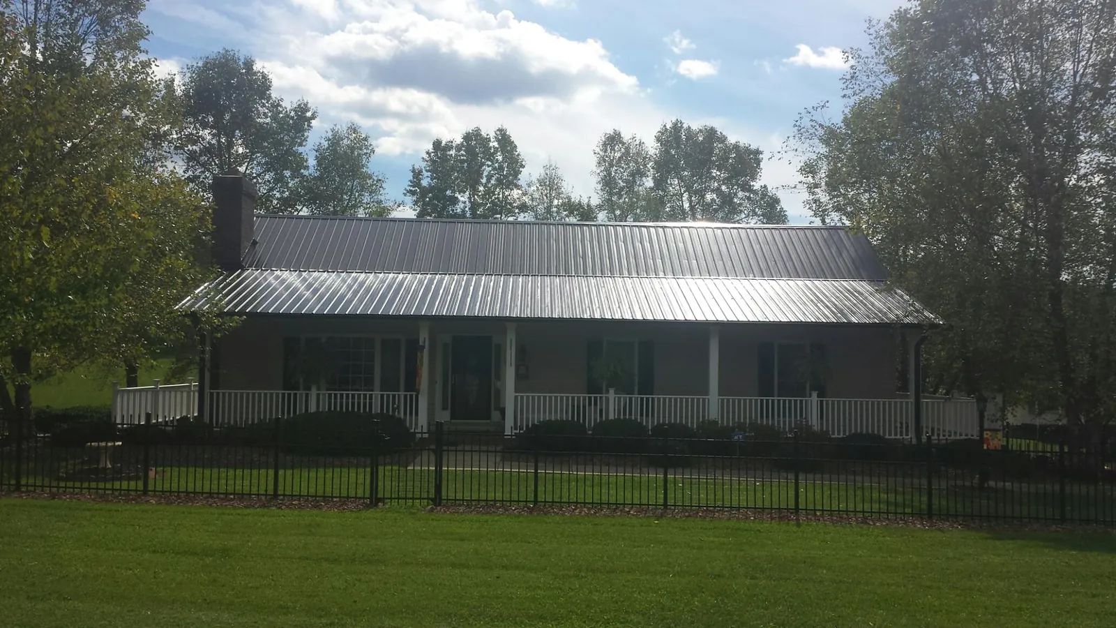Gray metal roof on a brick ranch with a full width front porch — Gutter Guard Installation work by our crew in Summerhill
