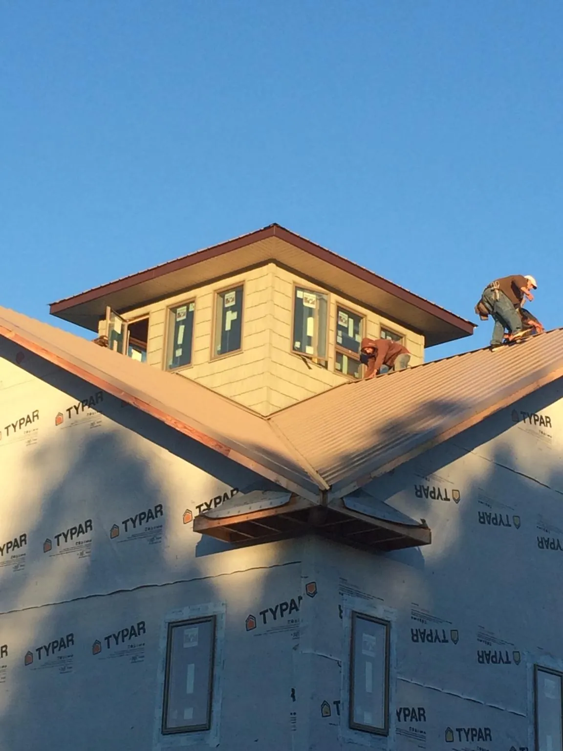 Roofers working around a rooftop cupola on a new metal roof at sunset — Roof Waterproofing in Summerhill by Roofing Brothers